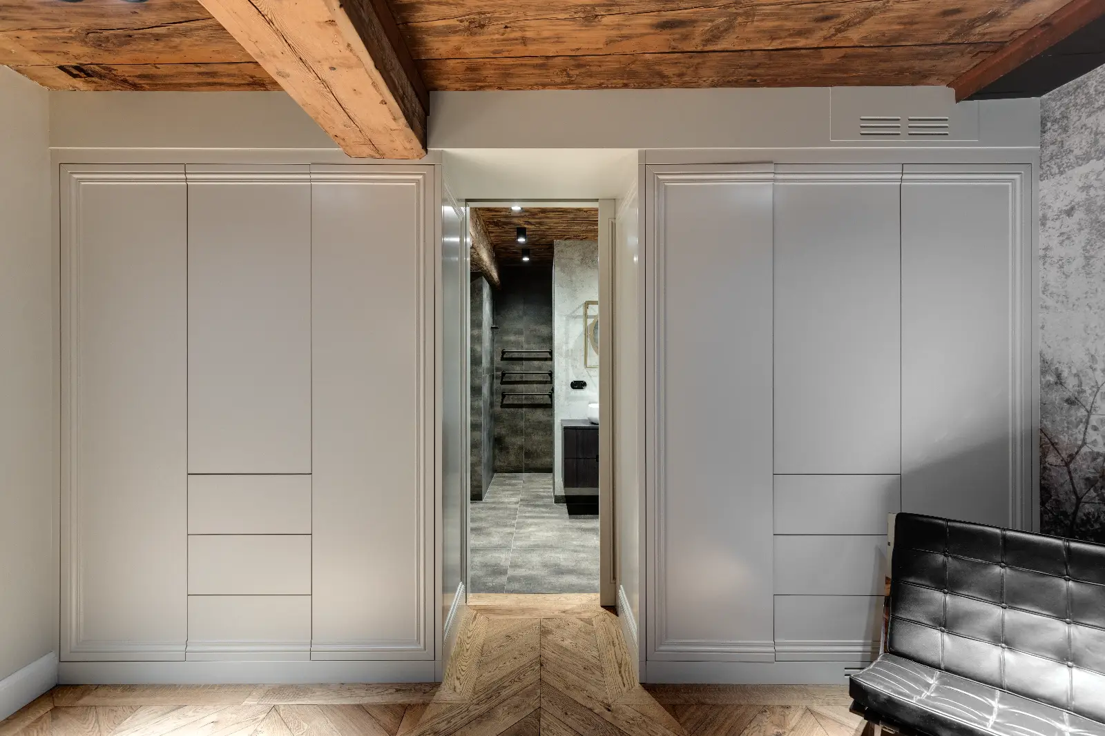 Modern interieurontwerp met symmetrische kasten, houten balken en herringbone vloer, gecreëerd door interieurontwerper uit de buurt van Amsterdam.