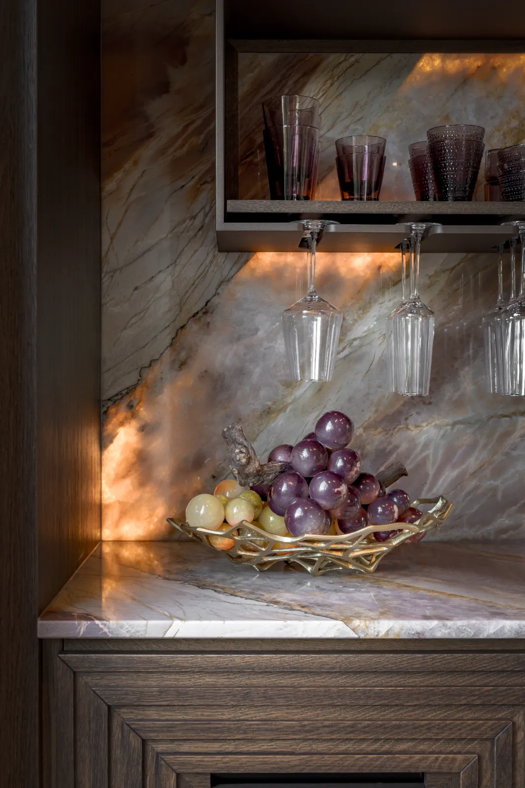 Luxe design keuken met marmeren achterwand, waarbij een fruitschaal met druiven op een stijlvol werkblad een warme en gezellige sfeer creëert.