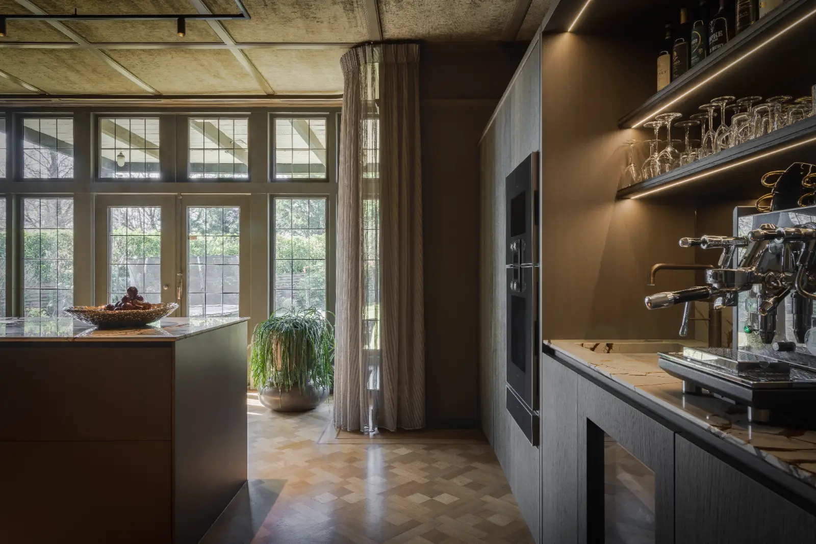 maatwerk interieurontwerp waarbij de keuken luxe is samengesteld met donkere fronten, veel licht en een houten vloer.