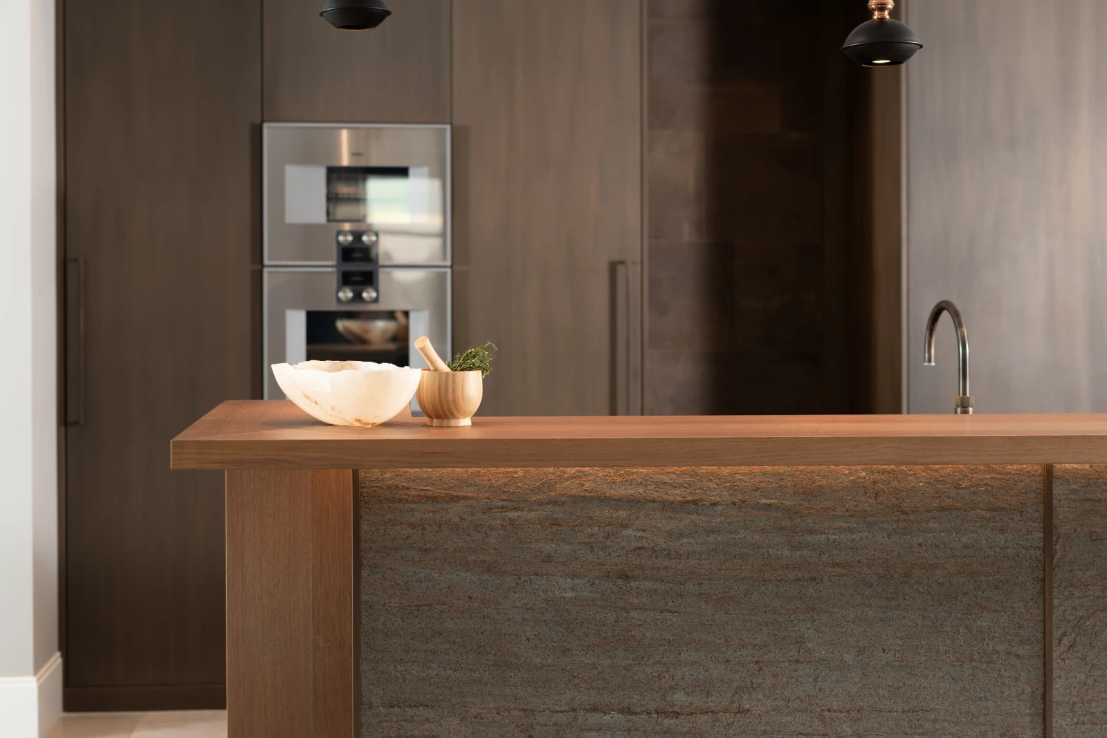 Een modern keuken herenhuis met houten kasten, een ingebouwde roestvrijstalen oven en magnetron, een minimalistische kraan en een houten eiland met decoratieve schalen. Warme, natuurlijke verlichting benadrukt de rijke texturen.