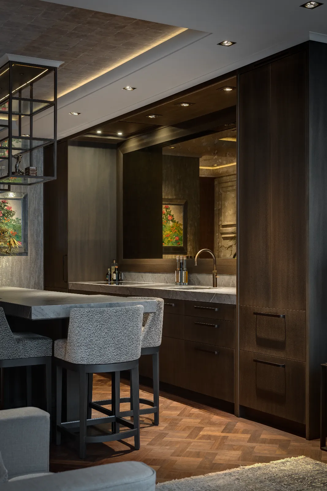 Modern keuken herenhuis met donkerhouten kasten, een marmeren aanrechtblad, ingebouwde spoelbak en geïntegreerde apparatuur. Op het schiereiland staan grijs gestoffeerde barkrukken; moderne verlichting en ingelijste kunst geven de ruimte warmte.